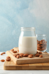 Glass of almond milk, almond seeds on white table again blue background, space for text