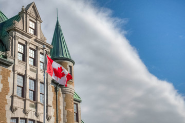 Canadian flag in the wind, beside historic building.