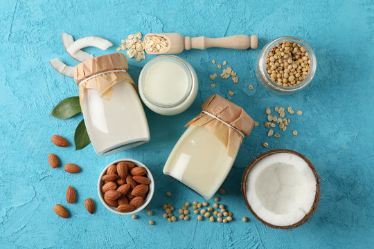 Composition with different types milk, coconut, soybeat seets, almound, oatmaet on blue background, space for text. Top view