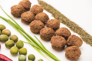close up view of olives, green onion, herb and falafel on white background