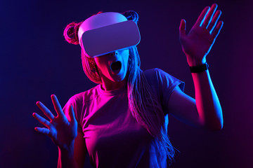 Woman is using virtual reality headset. Neon light studio portrait.