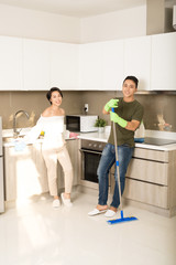 Young happy Asian couple is having fun while doing cleaning at home. Cleaning concept.