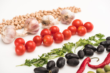 close up view of chickpea, garlic, cherry tomatoes, parsley, chili pepper, olives on white background