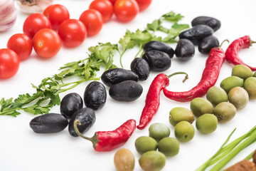 close up view of cherry tomatoes, parsley, olives, chili pepper on white background