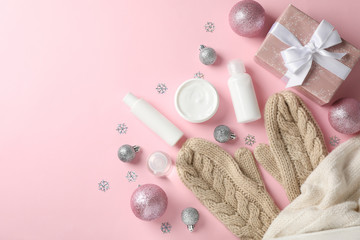 Set cosmetics, winter cream for skin, warm sweater and gloves on pink background, space for text. Top view