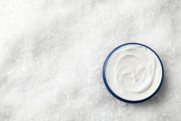 Jar of winter cream for skin on snowy background, space for text. Top view