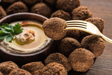 hummus and falafel served on wooden table with fork