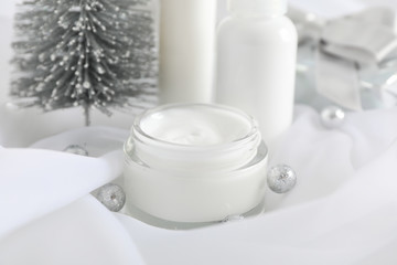 Set cosmetics, jar of winter cream for skin on white fabric background, closeup. Space for text