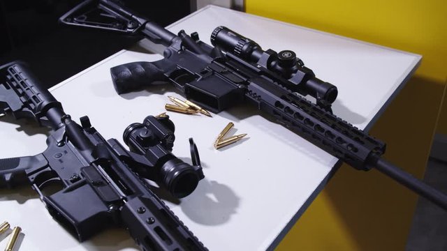 Guns with scope laying on a white table with ammunition