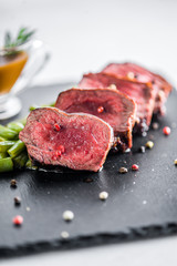 Steak medallion with vegetables and sauce on a black plate