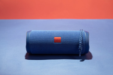 Blue wireless speaker on a bright red-blue background