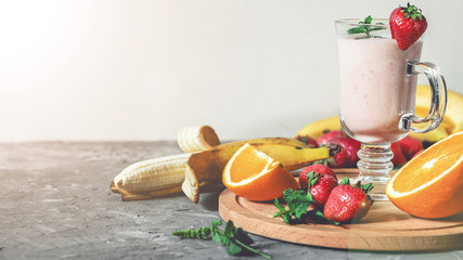 banana, strawberry and orange smoothies with mint on the table, front view