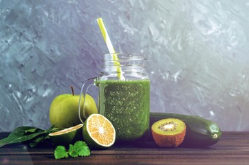 healthy green smoothie with ingredients on a wooden table: apple, kiwi, lime, spinach, mint, avocado, cucumber - 305420601