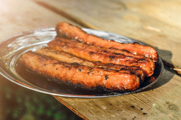 Sausages cooking on grill served on a plate. Food background with barbecue party, front view - 305420631