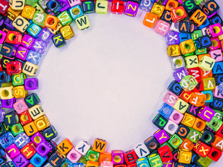 Top view or directly above of vivid colorful multicolored small plastic alphabet dice on white paper background. Copy space for education, kid learning concept and idea.