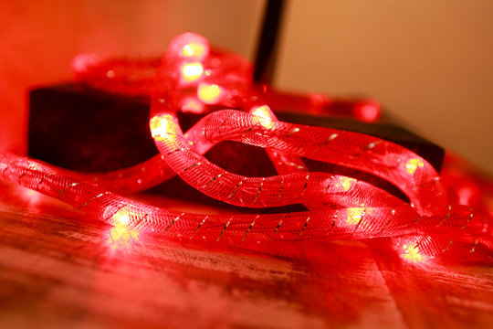 Bright red New Year and Christmas rice lights, shallow depth of field. Abstract red light background. Decorative flashing lights, ornaments to christmas celebration, holiday scene. Christmas concept.
