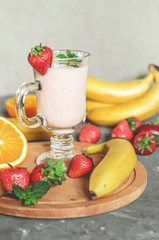 banana, strawberry and orange smoothies with mint on the table, front view - 305421034