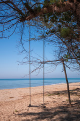 Beautiful tropical sea background swing on the sand beach with blue sky in sunny day