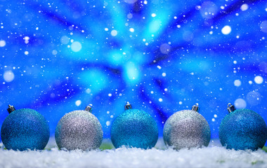 Abstract Christmas background,New Year and Christmas background. Blue and white Christmas toys lie on the snow, with a bright background. Falling snow.