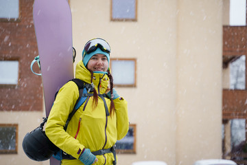 Obraz premium Photo of sportswoman with snowboard on background of building on snow resort