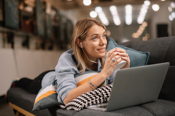 Young woman listening music. Beautiful woman lying on sofa. 