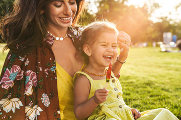 Mother having fun with her little daughter outdoors in nature green park.