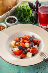 tomato salad with feta cheese and basil and glass of red drink on blue wooden table