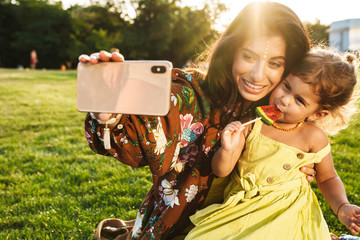 Mother with her little daughter take a selfie by mobile phone.