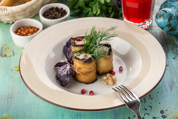 Eggplant rolls stuffed with cottage cheese and walnuts and glass of red drink on blue wooden table