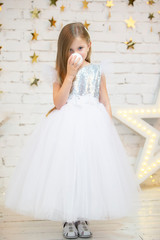 Beautiful child with a Christmas ball. Little model girl in a white dress. Beautiful preschooler.