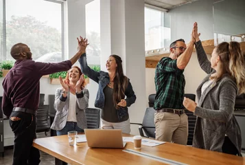 Foto op Plexiglas Diverse business team celebrating and giving high fives during boardroom meeting © JonoErasmus