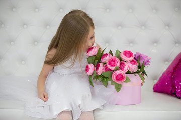 Beautiful child girl sniffing flowers.