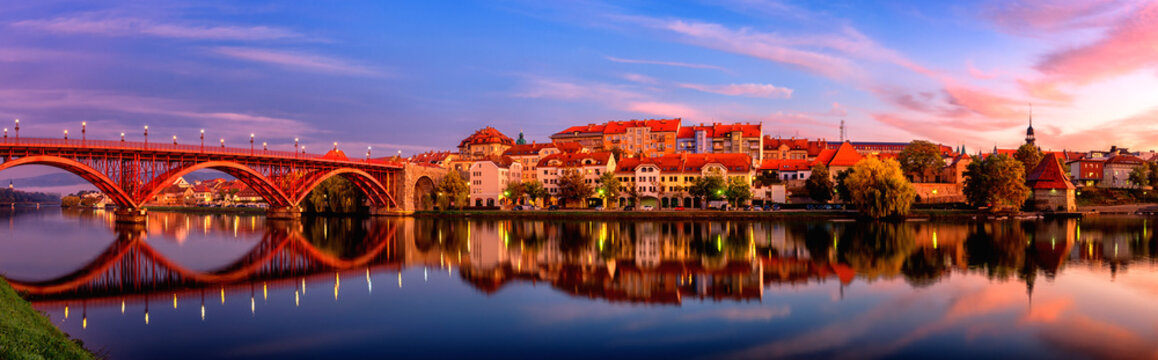 Amazing view of Maribor Old city, Main bridge (Stari most) on the Drava river before sunrise, Slovenia. Scenic cityscape with sky and reflection, travel background for wallpaper or guide book © larauhryn