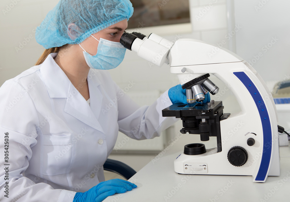 Poster medical worker looking in microscope and analysing material