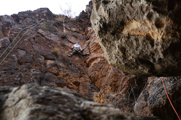 A rock climber climbs a rocky mountain. Mountain sport. Young man climbing challenging route
