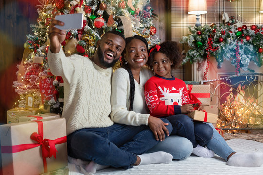 Afro family of three taking selfie near Christmas tree at home