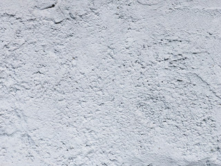 The texture of the light gray stone wall with a rough surface.