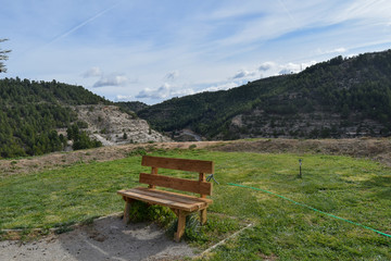 lonely wooden bench on top of a mountain with the sky and other mountains in the background