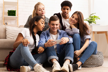 Teen guy showing new video on cellphone to friends