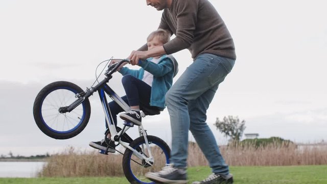 Father and son riding bike outdoors by the lake, spending quality time together