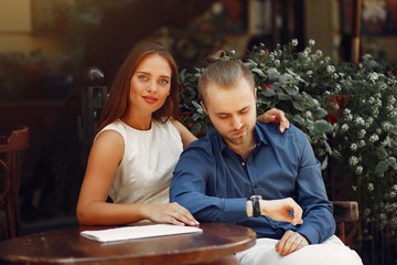 Cute couple in a city. Lady in a white dress. Pair sitting on a cafe