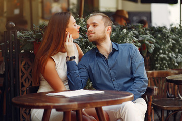 Cute couple in a city. Lady in a white dress. Pair sitting on a cafe