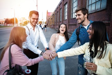 Group of friends stacking hands outdoor - Happy young people having fun joining and celebrating...