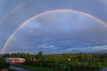 A piece of rainbow in the sky against the background of rain clouds.