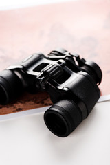 selective focus of binoculars near map on white