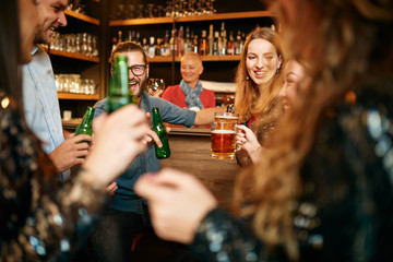Group of friends drinking beer, chatting and having good time at pub. Night out.