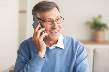 Elderly Man Talking On Cellphone Sitting On Couch At Home