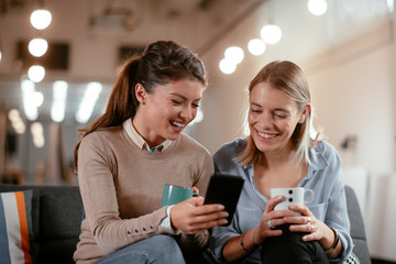 Best friends. Two beautiful woman sitting on sofa. Sisters at home