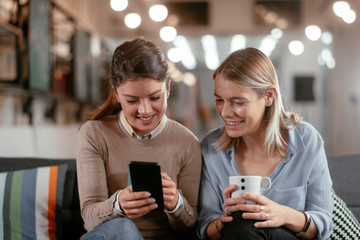 Best friends. Two beautiful woman sitting on sofa. Sisters at home