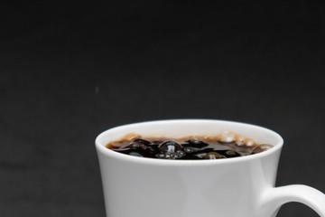 Obraz na płótnie Canvas close-up pouring hot black coffee into a white cup, fresh coffee, black background